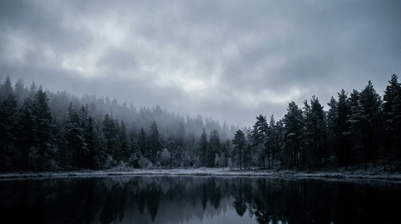A cold Nordic forest and still lake under heavy fog at blue hour