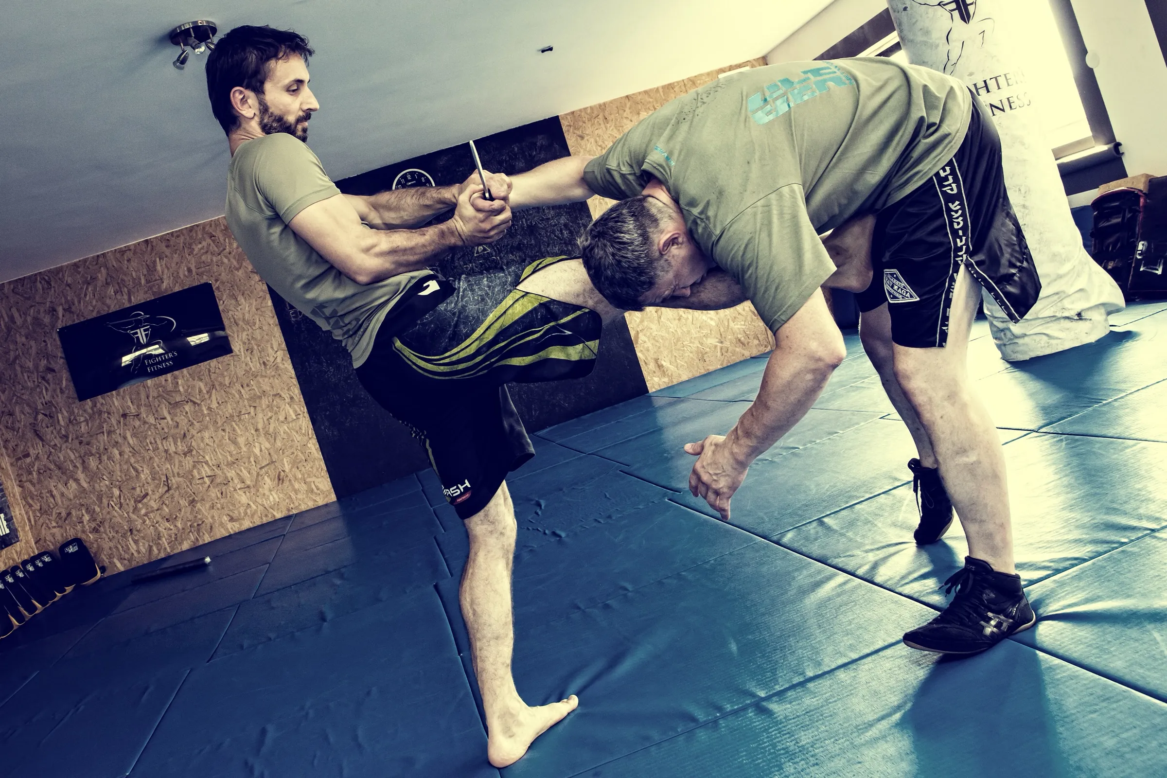 A knee strike controlled in a clinch during a fighting-skills drill